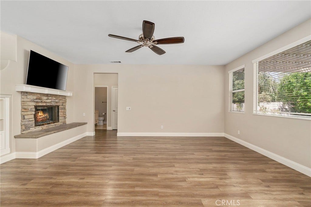 32440 Magenta Court, Temecula, CA 92592 Another View Of The Spacious Family Room Highlighting The Beautiful Stone-Surround Fireplace, Wood-Look Flooring, Ceiling Fan, And Abundant Natural Light.
