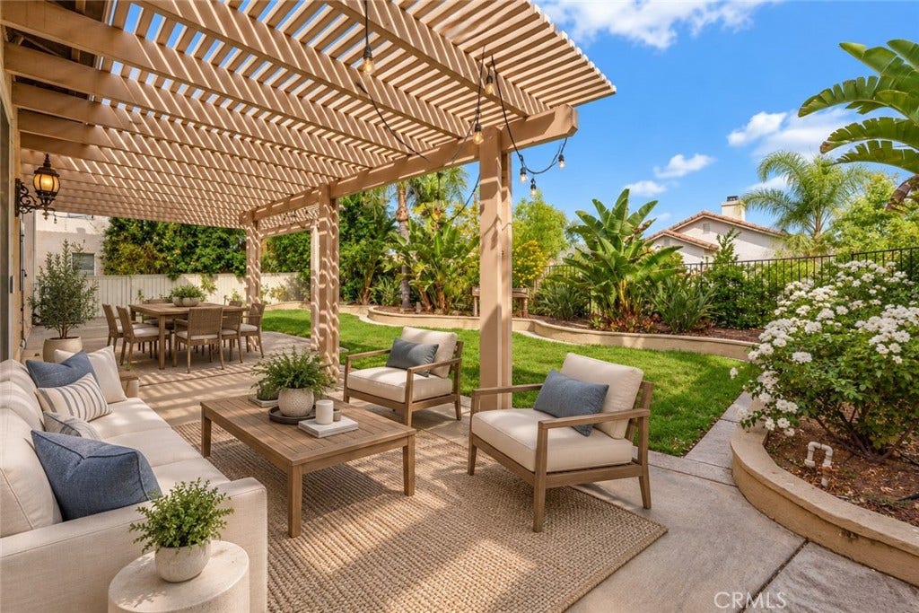 32440 Magenta Court, Temecula, CA 92592 Inviting Backyard Patio Featuring A Spacious Pergola, Comfortable Outdoor Seating Areas, And Beautiful Tropical Landscaping, Perfect For Relaxing Or Entertaining. Digitally Staged