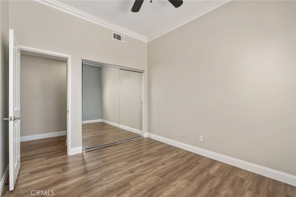 32440 Magenta Court, Temecula, CA 92592 Another View Of The Secondary Bedroom Highlighting The Mirrored Closet Doors, Elegant Crown Molding, Generous Floor Space, And Attractive Wood-Look Flooring.
