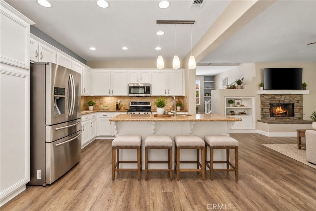 32440 Magenta Court, Temecula, CA 92592 Spacious Open-Concept Kitchen Featuring A Large Center Island With Breakfast Bar Seating, Stainless Steel Appliances, Recessed Lighting, And A Beautiful View Into The Family Room With Stone-Surround Fireplace. Digitally Staged