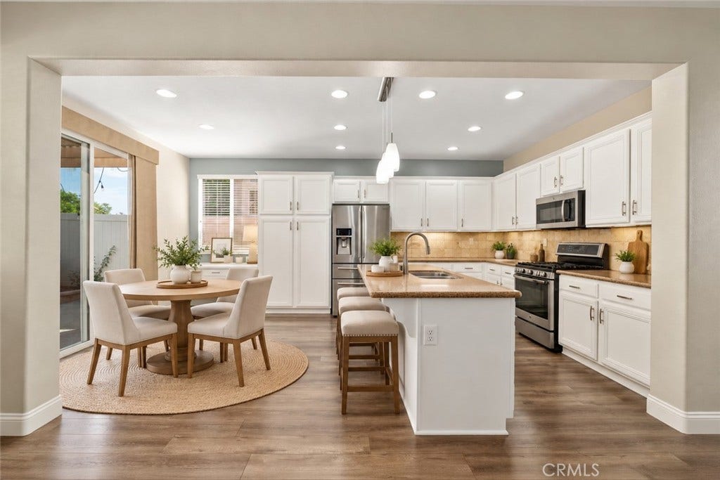 32440 Magenta Court, Temecula, CA 92592 Spacious Kitchen And Adjacent Dining Area Featuring White Cabinetry, Stainless Steel Appliances, A Large Center Island, Recessed Lighting, And Sliding Glass Door Access To The Backyard. Digitally Staged