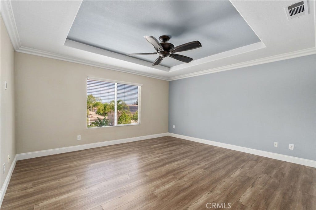32440 Magenta Court, Temecula, CA 92592 Beautiful Primary Suite Featuring A Decorative Tray Ceiling With Crown Molding, Ceiling Fan, Attractive Wood-Look Flooring, And A Large Window Providing Abundant Natural Light.