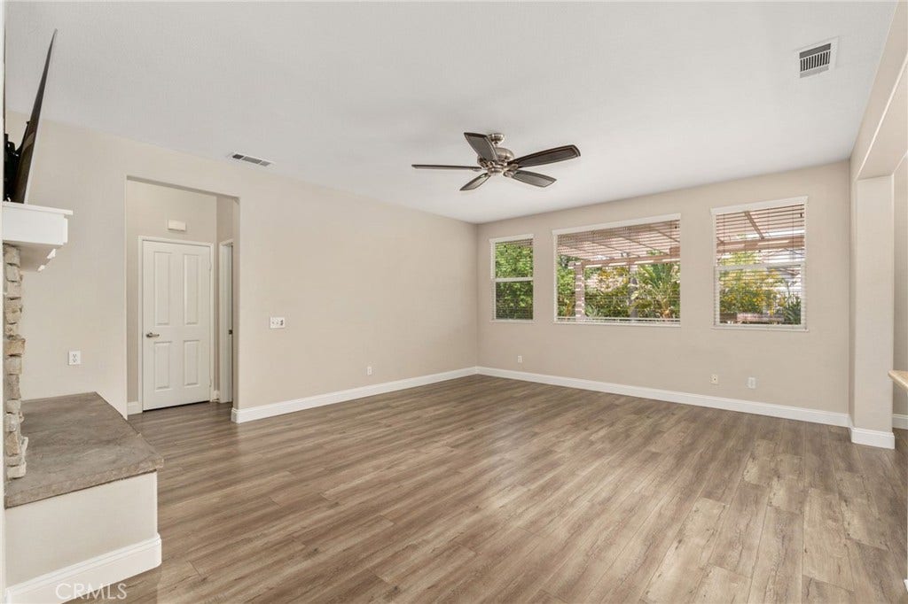 32440 Magenta Court, Temecula, CA 92592 Inviting Family Room Featuring Wood-Look Flooring, A Ceiling Fan, And Large Windows Overlooking The Backyard, Creating A Comfortable Space For Relaxation And Entertaining.