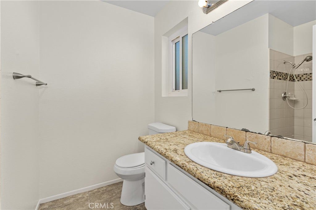 42329 Via Consuelo, Temecula, CA 92592 Primary bathroom featuring a granite-topped vanity, single sink, and tiled shower with decorative mosaic accents.