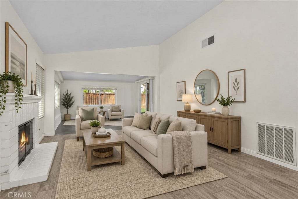 42329 Via Consuelo, Temecula, CA 92592 Spacious living area featuring a charming white brick fireplace, generous natural light, and an open layout extending toward the enclosed patio. Digitally Staged