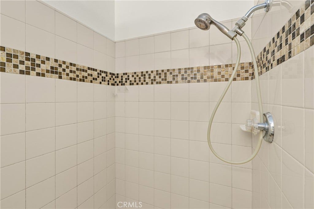42329 Via Consuelo, Temecula, CA 92592 A closer look at the primary bathroom shower featuring a tiled surround, decorative mosaic accents, and a handheld showerhead.