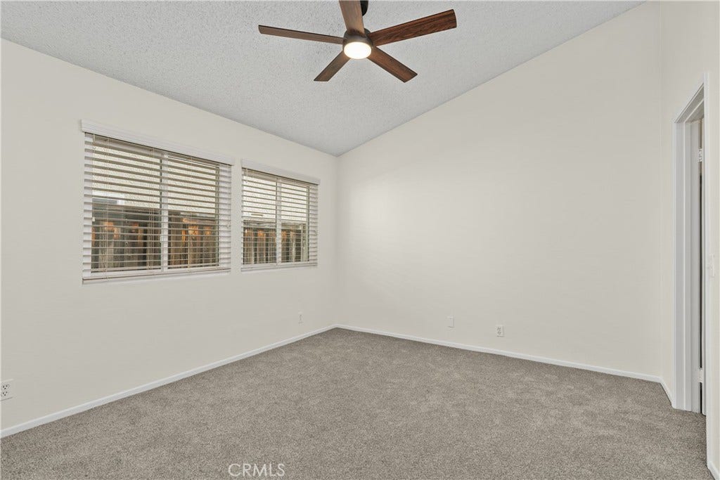 42329 Via Consuelo, Temecula, CA 92592 The comfortable primary bedroom features soft carpeting, a ceiling fan, and two windows providing natural light.
