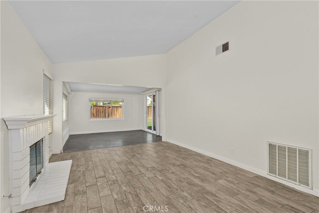 42329 Via Consuelo, Temecula, CA 92592 Spacious living area featuring a charming white brick fireplace, generous natural light, and an open layout extending toward the enclosed patio.