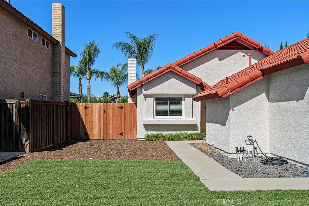42329 Via Consuelo, Temecula, CA 92592 Side view of the home showcasing the maintained lawn, concrete walkway, and gated yard access.