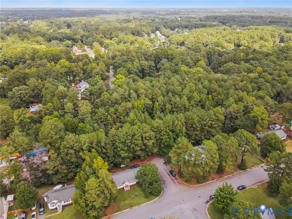 Aerial view of property and surrounding area featuring a forest