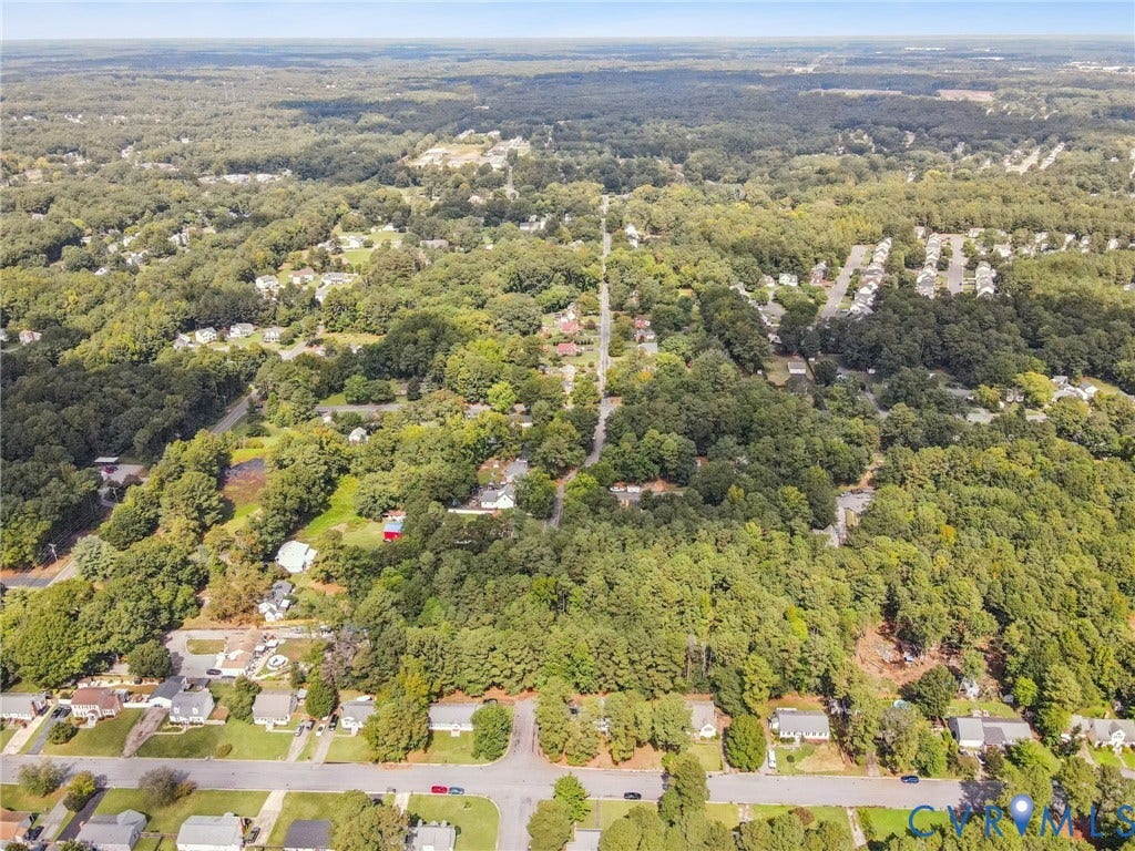 Aerial view of property's location featuring a heavily wooded area and nearby suburban area