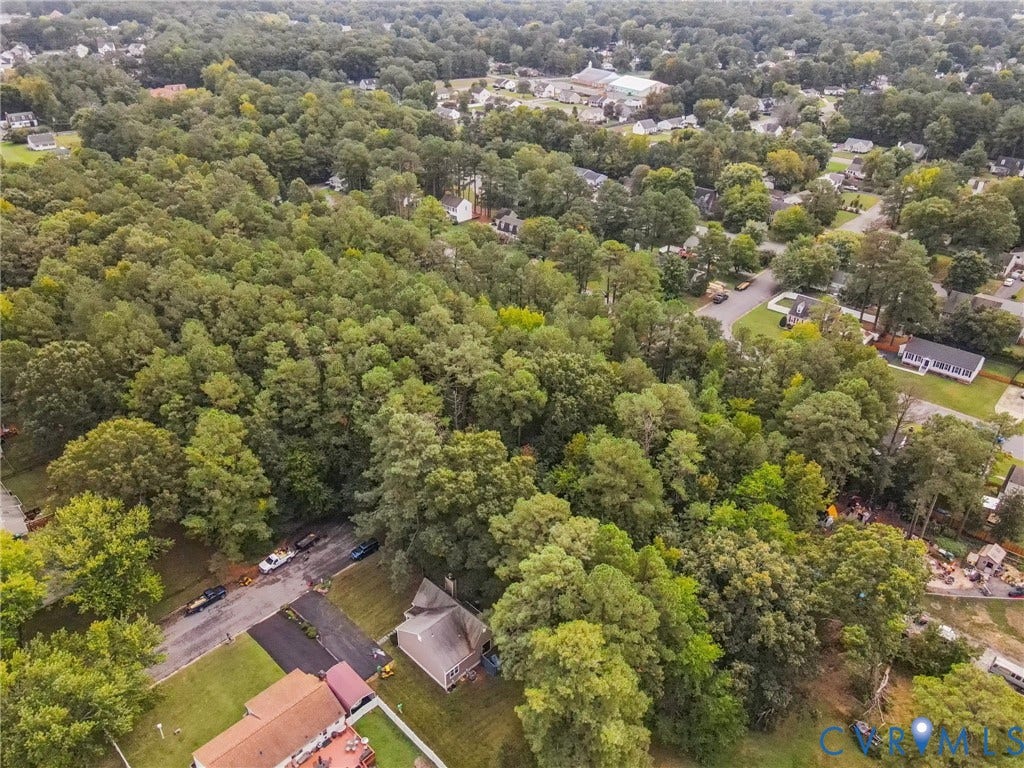 Aerial view of property and surrounding area with a forest