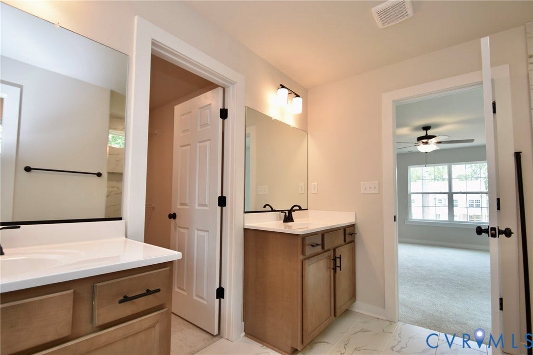53 Porkchop Court, Louisa, VA 23093 Dual vanities with white countertops, light wood-finish cabinetry, and black hardware