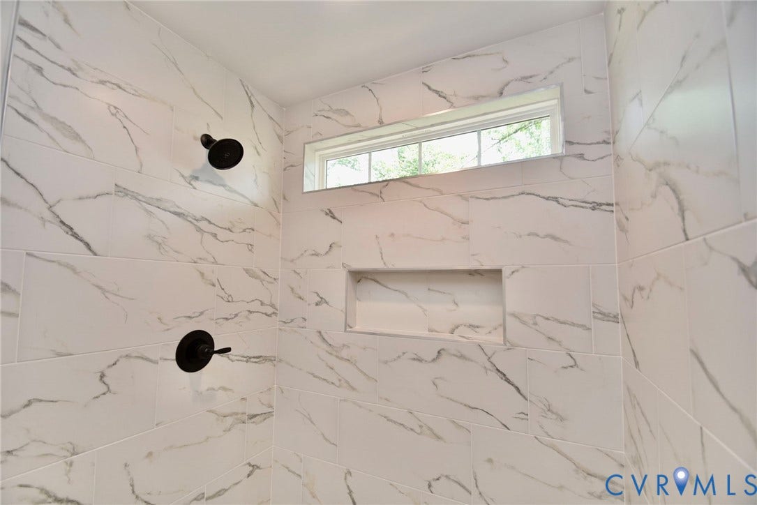 53 Porkchop Court, Louisa, VA 23093 White marble-look tiled shower with matte black fixtures, built-in recessed niche, and an upper transom window