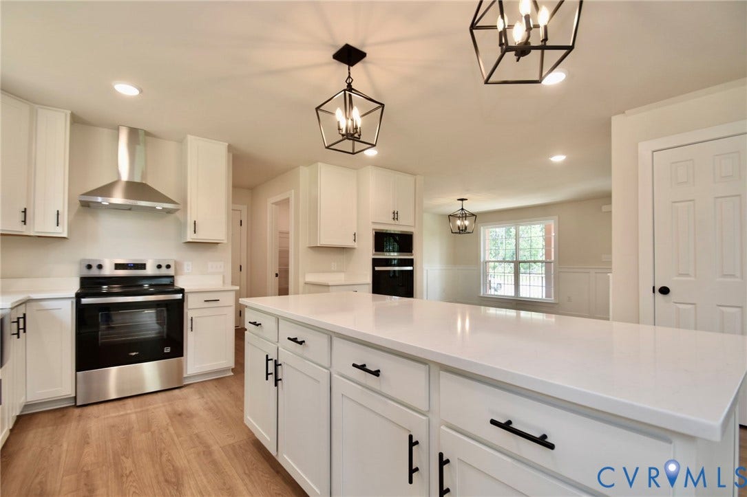 53 Porkchop Court, Louisa, VA 23093 Kitchen featuring white shaker cabinetry, stainless steel appliances, a large center island with a solid surface countertop, and wood-finish flooring