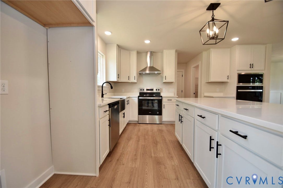 53 Porkchop Court, Louisa, VA 23093 White cabinetry, light wood-finish flooring, stainless steel appliances, and a central island with a solid surface countertop