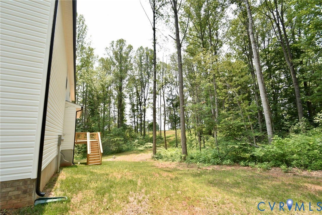53 Porkchop Court, Louisa, VA 23093 White horizontal siding exterior with a wooden deck and stairs, surrounded by a natural treeline