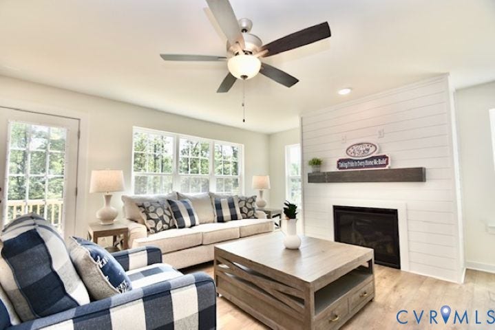 54 Porkchop Court, Louisa, VA 23093 Living area featuring a fireplace with a shiplap surround, wood-finish flooring, a ceiling fan, and multiple windows