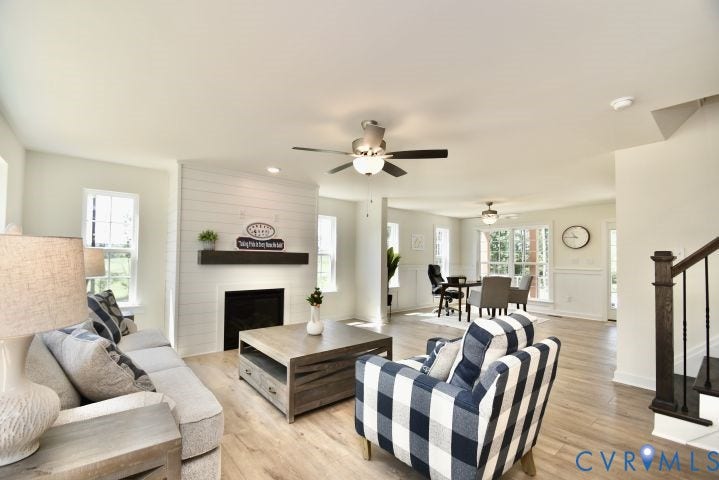 54 Porkchop Court, Louisa, VA 23093 Wood-finish flooring, shiplap-accented fireplace with dark mantel, ceiling fans, and a staircase with dark wood banister and balusters