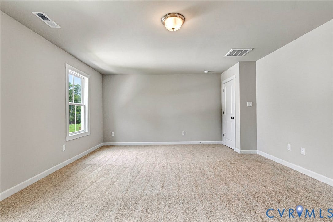 Neutral-toned carpeting, white trim, and a white interior door with dark hardware