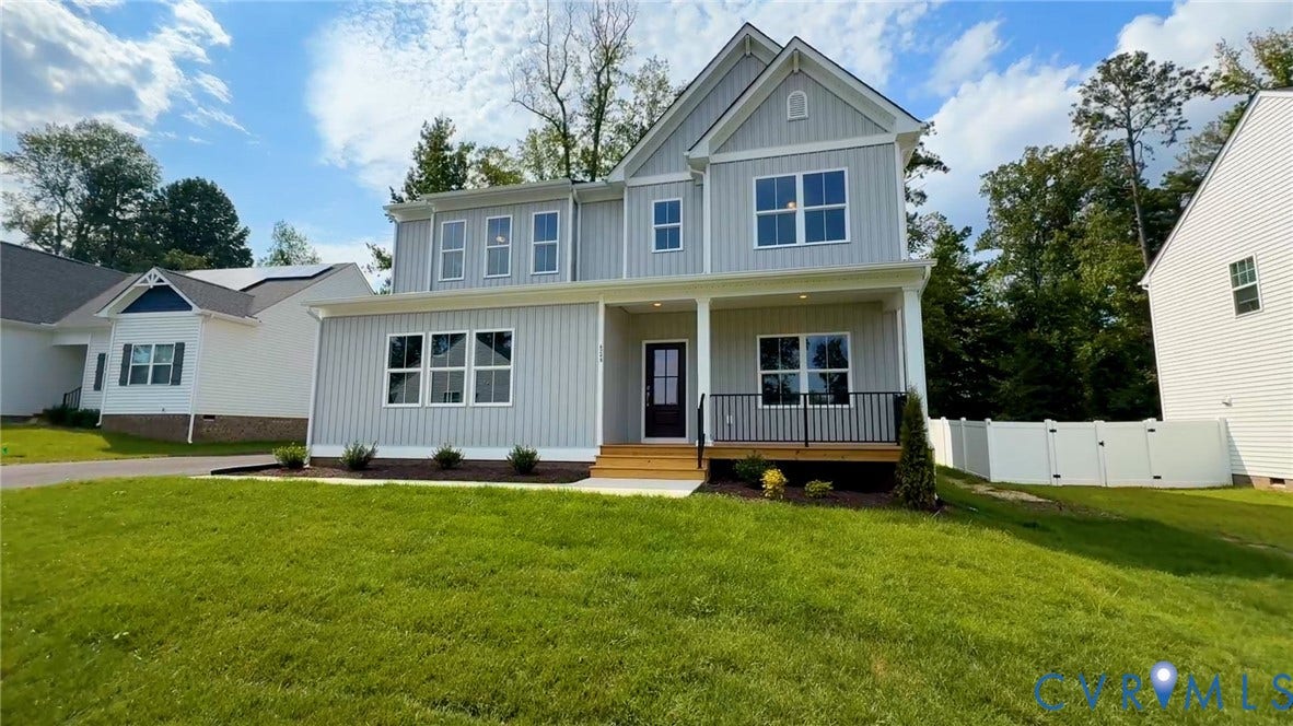 Two-story property featuring light gray siding, a covered front porch with a black railing, and a white privacy fence