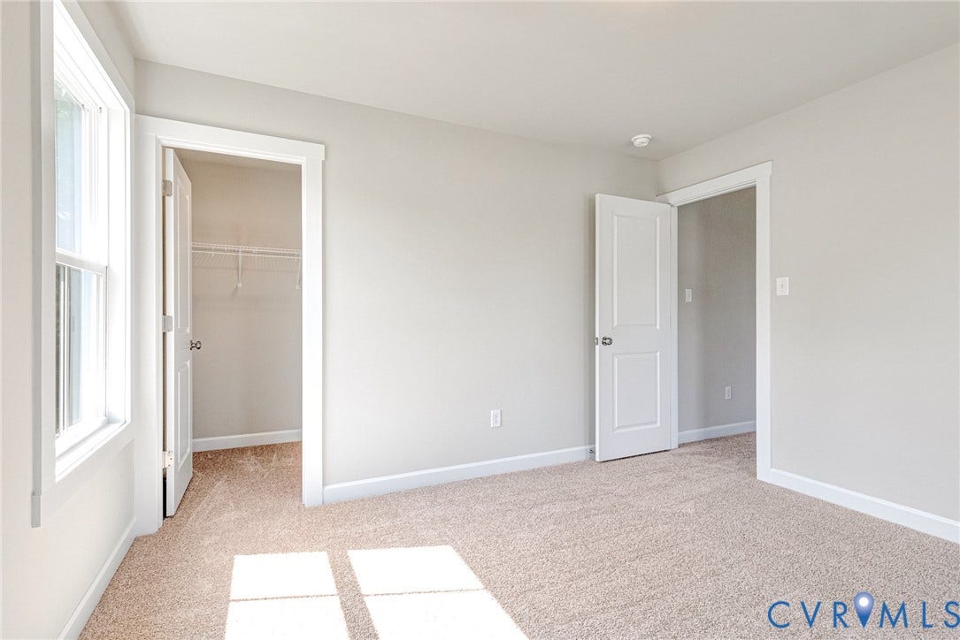 Light gray wall finishes, neutral carpet flooring, white trim, and white two-panel interior doors