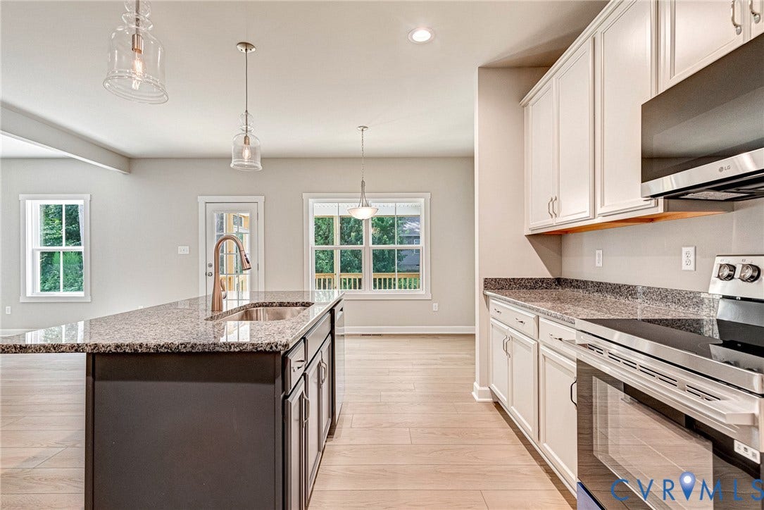 Kitchen featuring an island with a stainless steel dishwasher, white upper cabinetry, and granite countertops