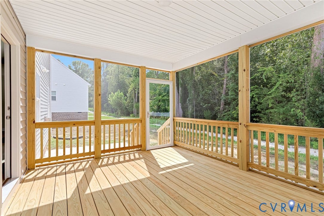 Spacious screened porch featuring wood decking, wood railings, and a white beadboard ceiling