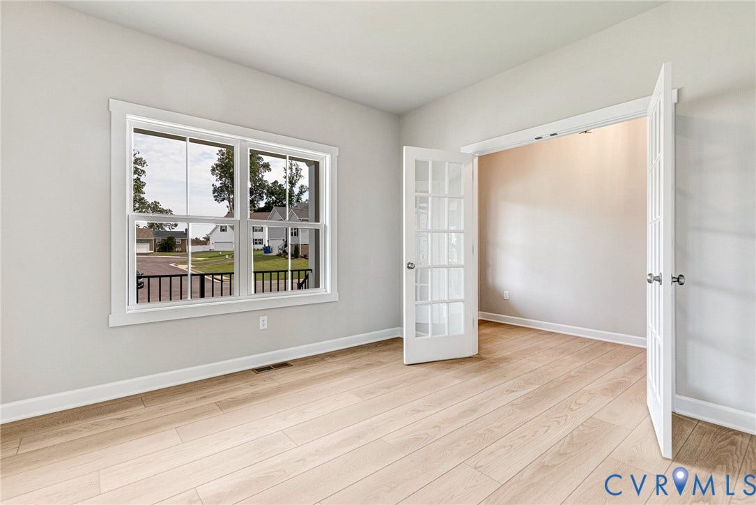 Light wood-finish flooring, white trim, and a large window