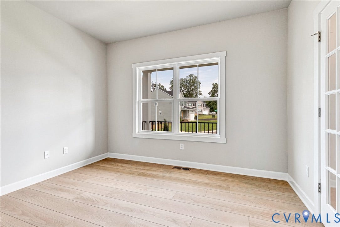 Light-toned wood-finish flooring, white trim, a large window, and French doors