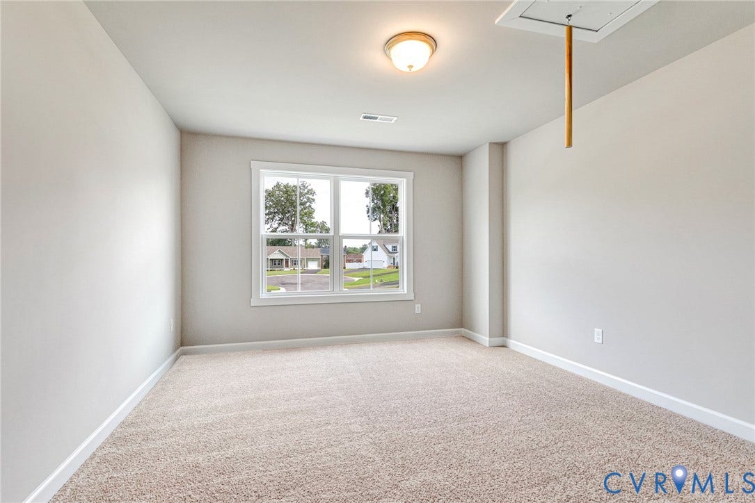 Neutral wall color, carpeted flooring, window with white trim, and ceiling-mounted light fixture