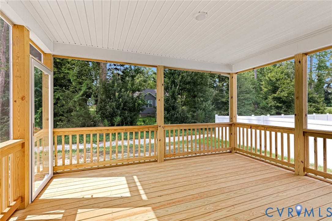 Spacious screened porch featuring a natural wood-finish deck, white railing, and a white beadboard ceiling