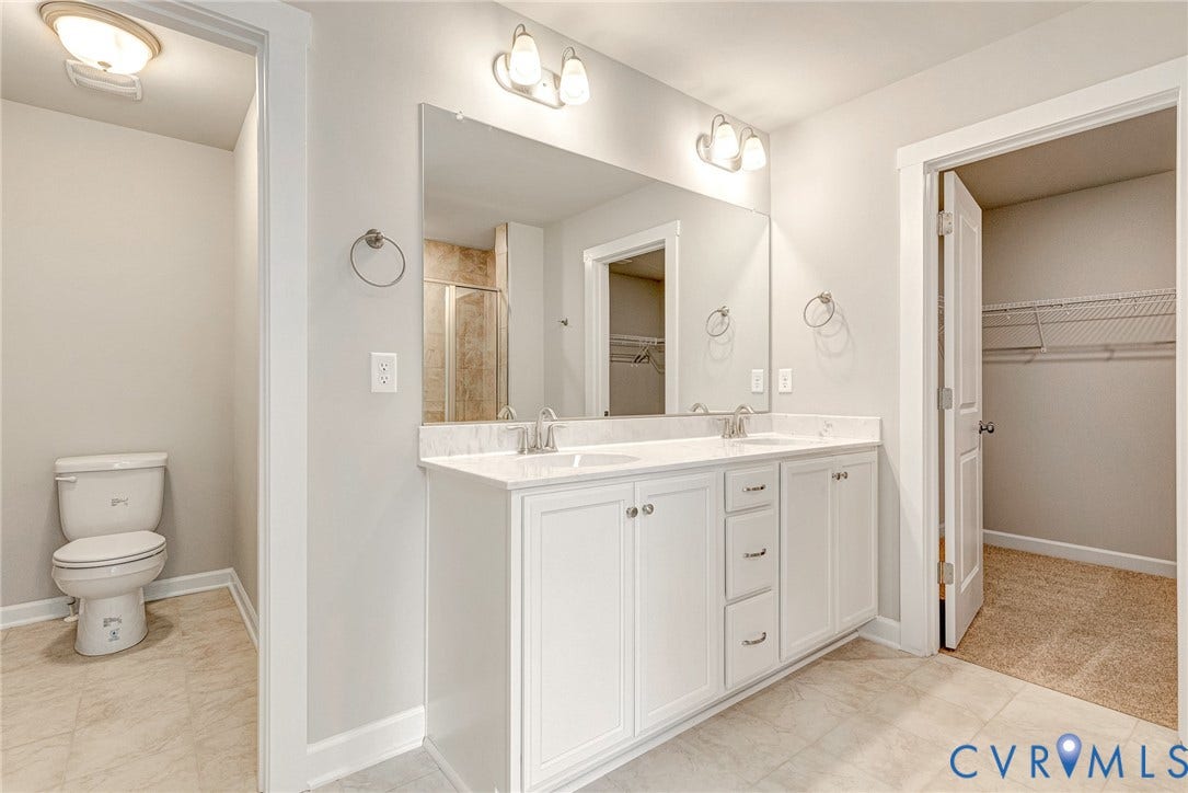 Double vanity with white cabinetry, dual sinks, and a large mirror