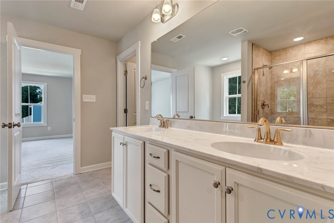 Dual vanity with a stone countertop, individual undermount sinks, and gold-finish faucets