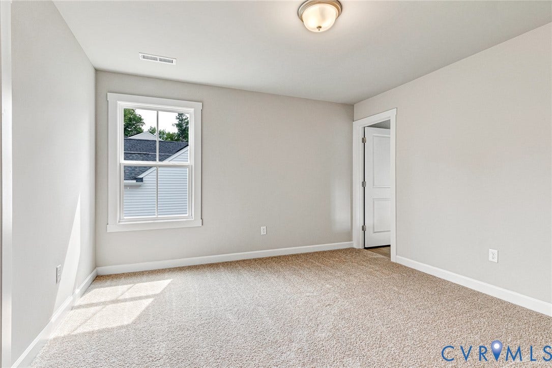 Neutral wall paint, plush carpeting, white trim, single window, and a ceiling-mounted light fixture