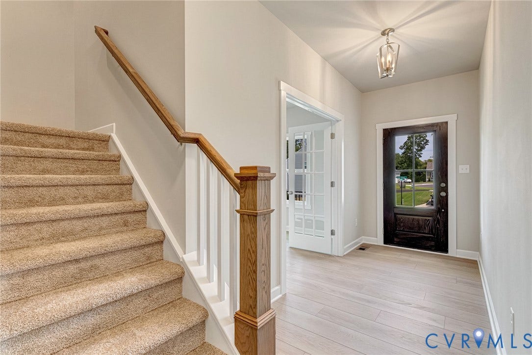 Entryway featuring a dark wood-finish front door, light wood-finish flooring, and a contemporary ceiling fixture