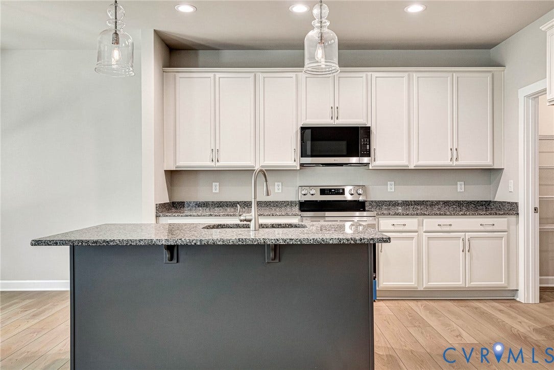 Open concept living space featuring light wood-finish flooring, a fireplace with a white mantel, and recessed lighting