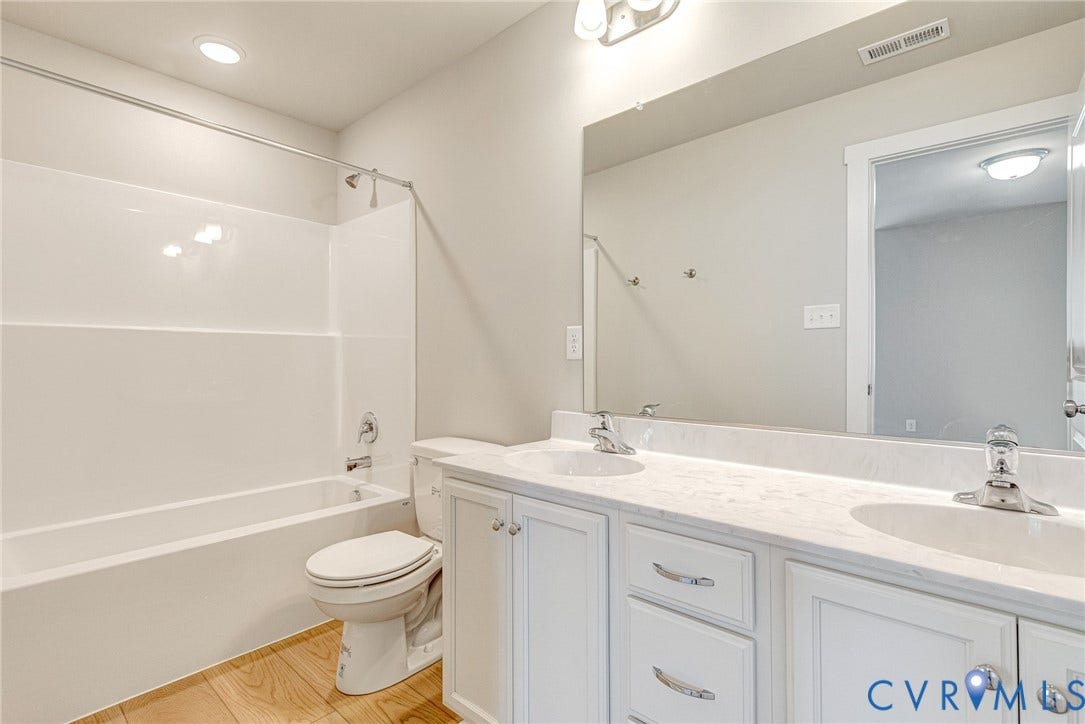 Dual vanity with integrated sinks, white cabinetry, and a large wall-mounted mirror