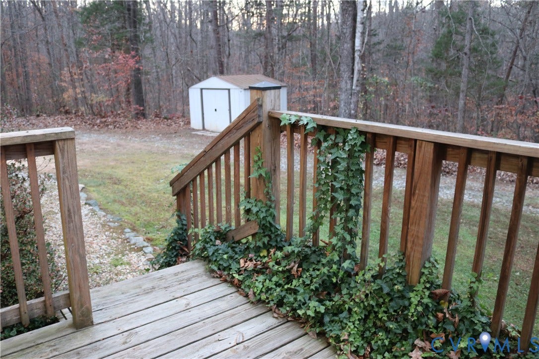 128 Quarry, Quarry, Cumberland, VA 23040 Deck featuring a view of trees, a storage unit, and a lawn