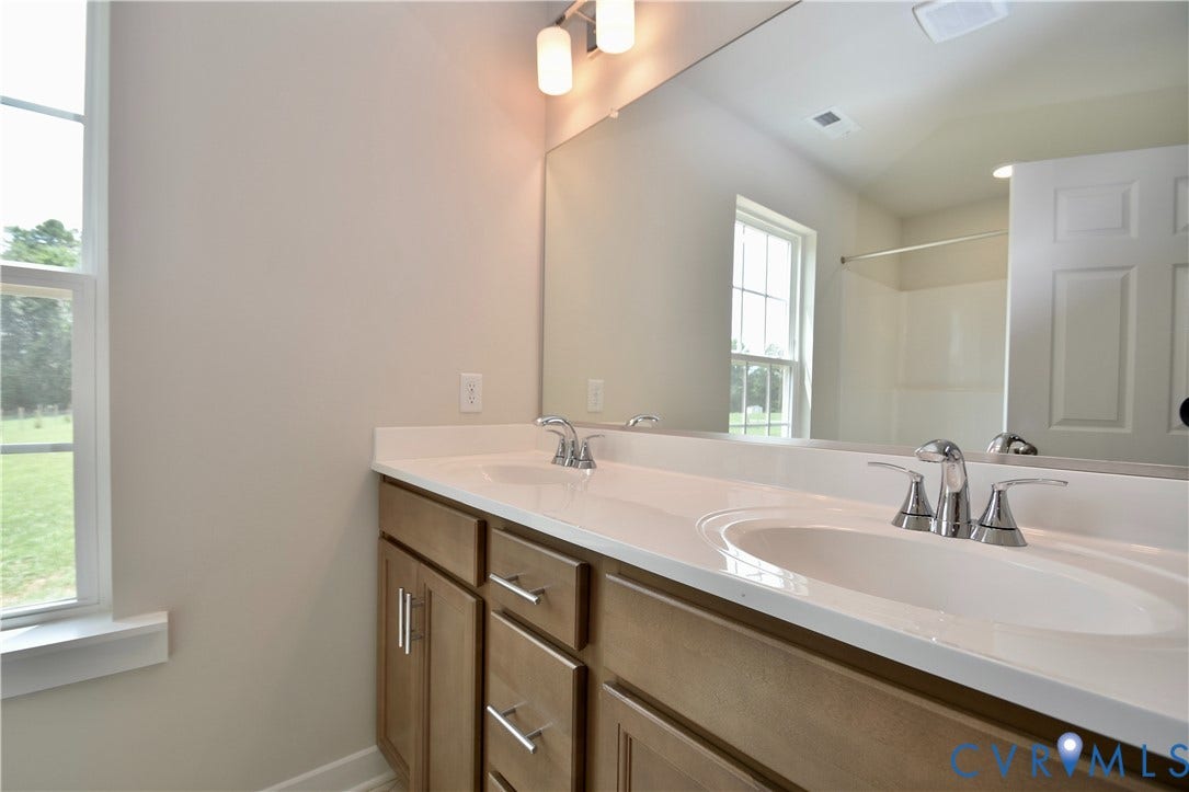 Dual vanity with wood-finish cabinetry, chrome fixtures, and a large mirror