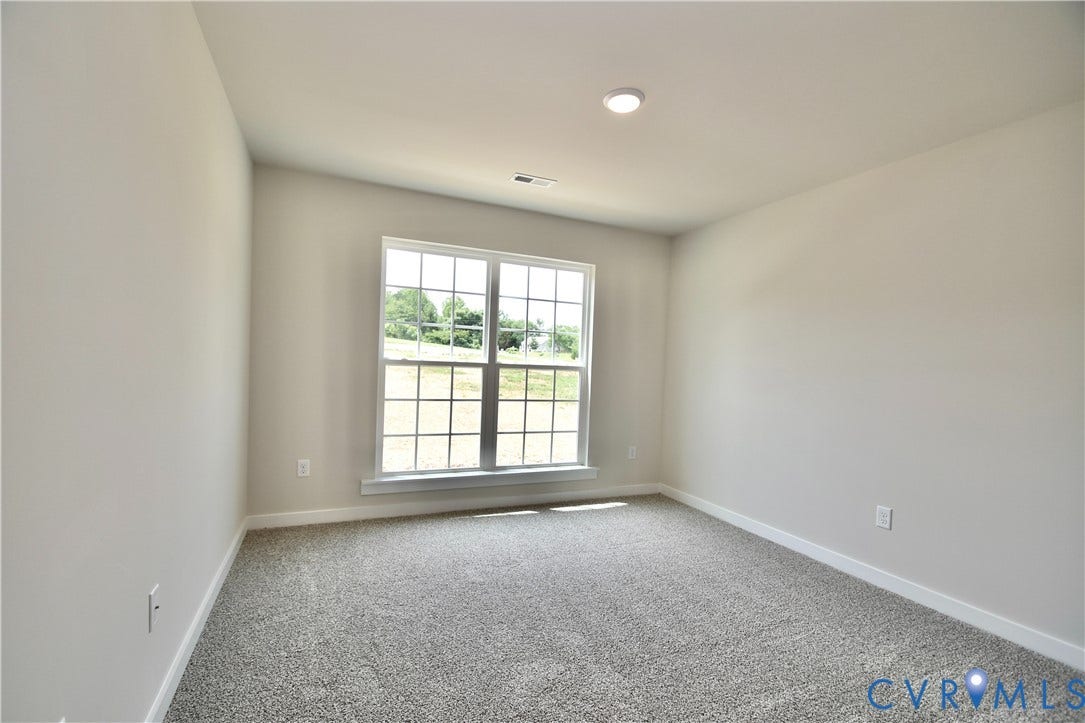 Bright interior space featuring a double-hung window, light gray carpeting, and recessed ceiling lighting