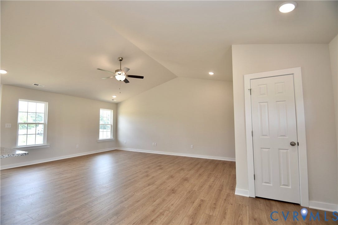 Spacious room featuring wood-finish flooring, vaulted ceiling, and recessed lighting