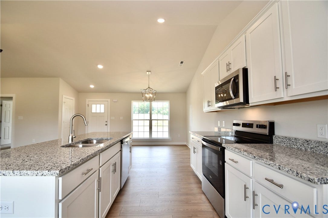 Kitchen featuring white cabinetry, granite countertops, stainless steel appliances, and wood-finish flooring