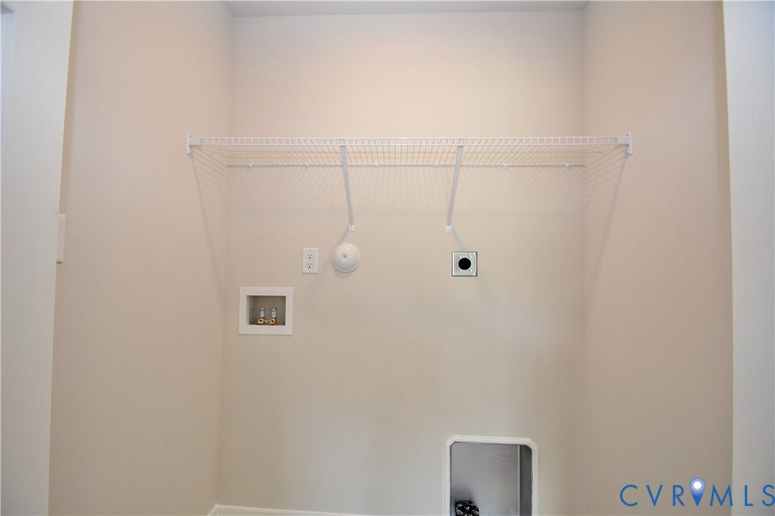 Laundry area featuring a wire storage shelf, electrical outlets, and plumbing hookups