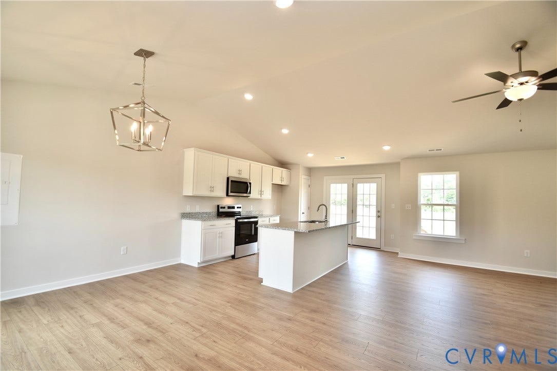 Open-concept living area featuring wood-finish flooring, a vaulted ceiling, and recessed lighting