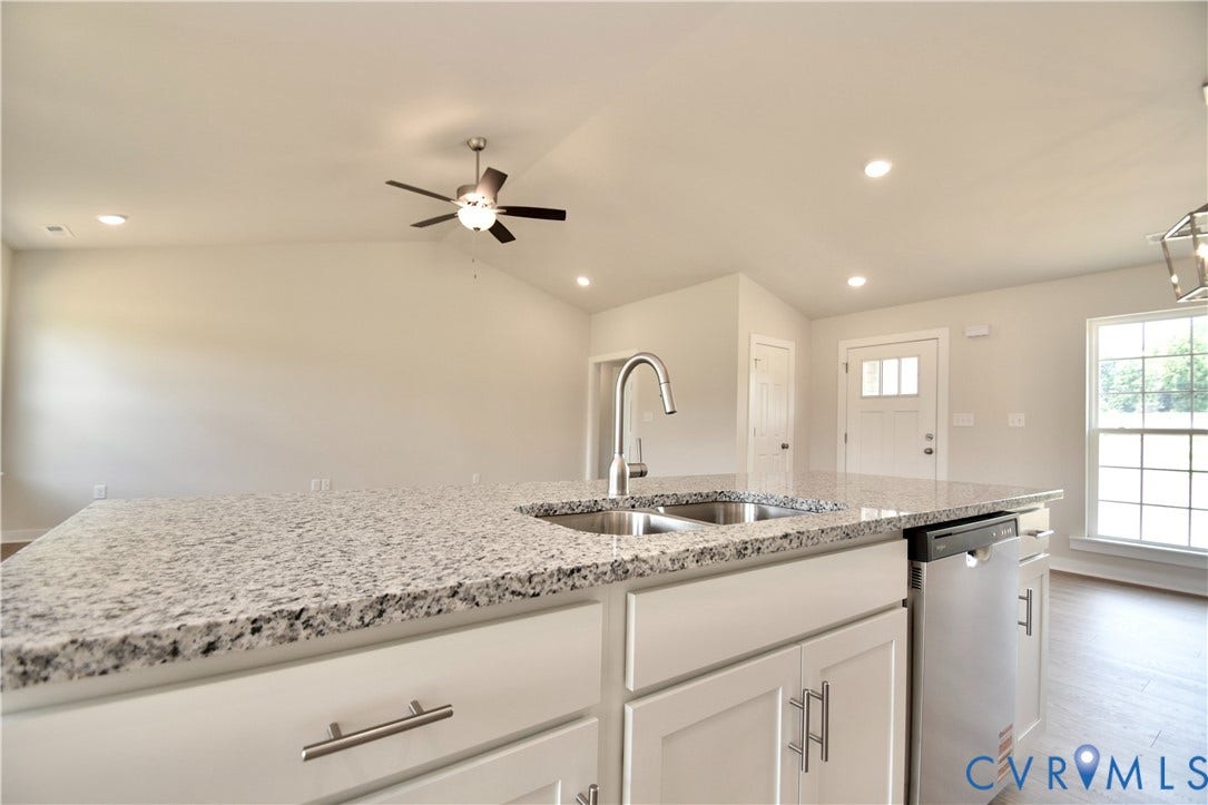 Kitchen island featuring a double basin stainless steel sink, gooseneck faucet, and light-toned granite countertop