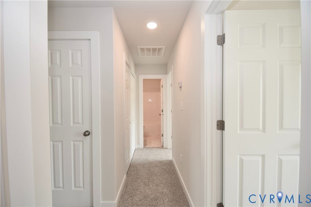 Hallway featuring light gray carpeting, recessed lighting, and six-panel interior doors