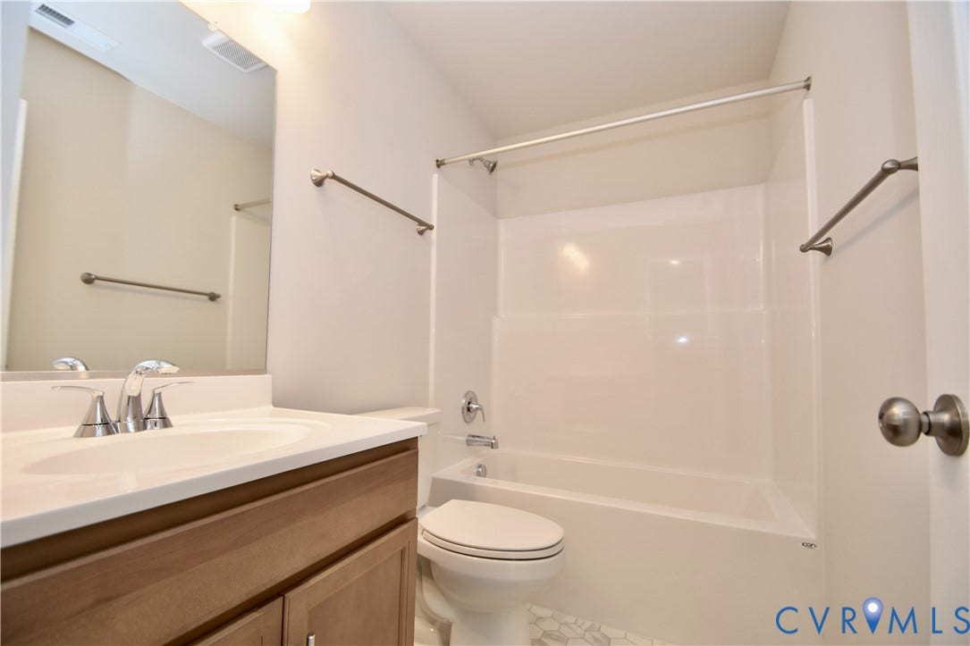Bright bathroom featuring a single vanity with wood-finish cabinetry, a white countertop with integrated sink, and brushed nickel fixtures