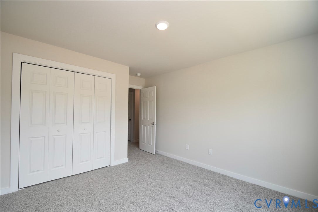 Interior room featuring neutral wall paint, light gray carpet, and white bi-fold closet doors