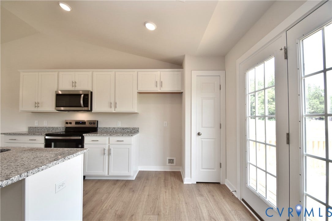 Kitchen area featuring white cabinetry, light-toned wood-finish flooring, and light-toned speckled countertops